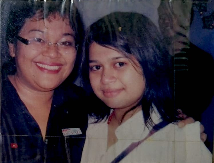 A woman and a girl smiling at the camera in an old photograph.